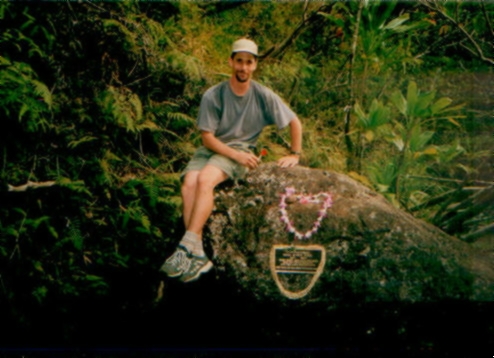 Jim sitting on boulder with memorial plaque